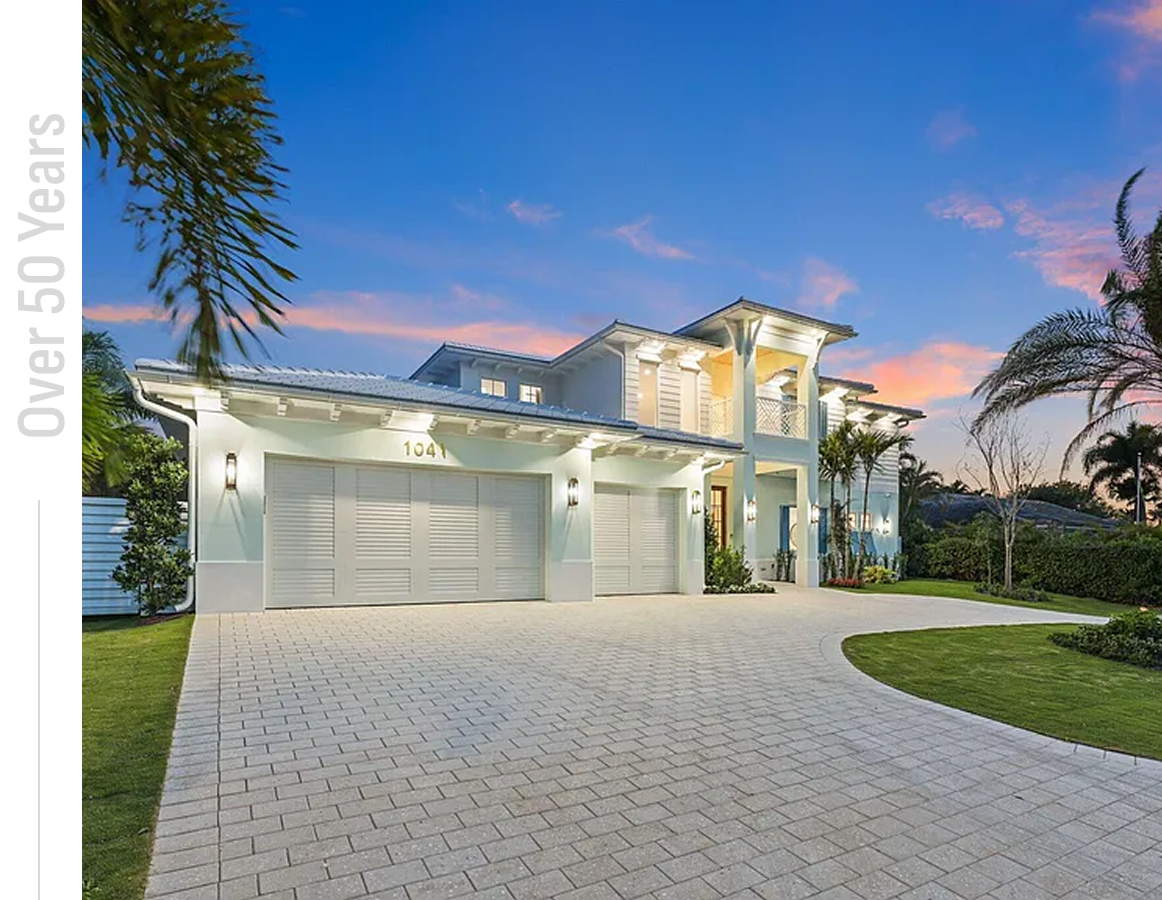 Modern house with large driveway at sunset.